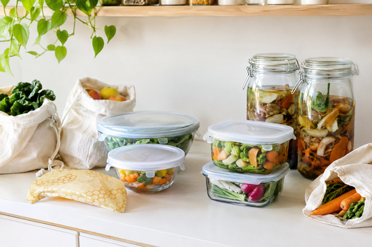 Reusable kitchen items including silicone lids, beeswax wrap, cloth bags, and a jar of vegetable scraps